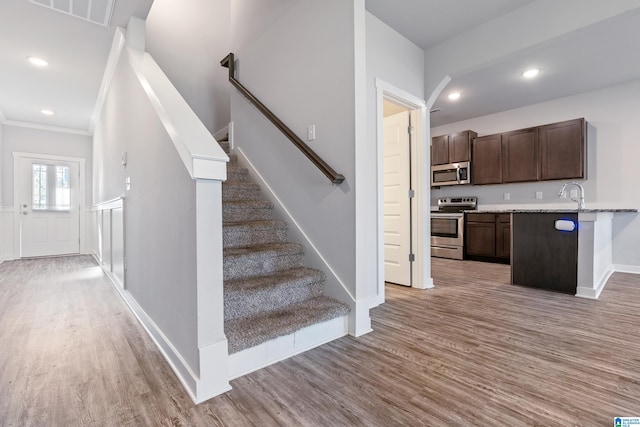 stairway with wood-type flooring and ornamental molding