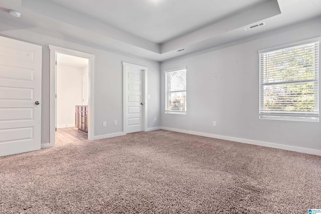 unfurnished bedroom featuring carpet and a tray ceiling