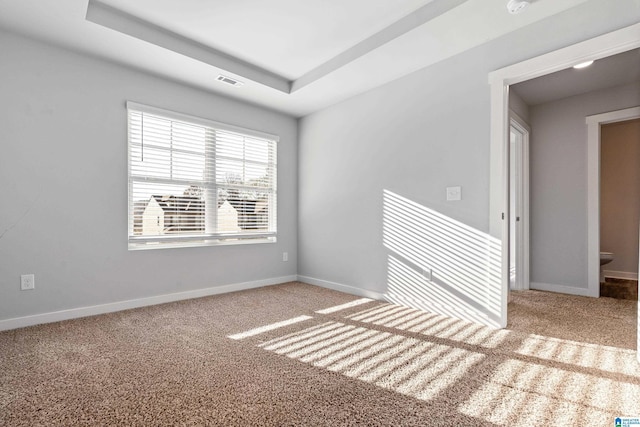 carpeted empty room with a tray ceiling