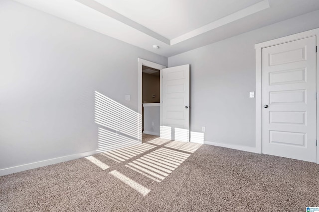 carpeted empty room featuring a raised ceiling