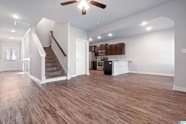 unfurnished living room featuring dark hardwood / wood-style floors, ceiling fan, ornamental molding, and sink