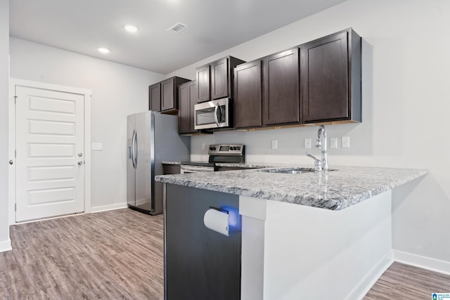 kitchen featuring dark brown cabinets, stainless steel appliances, light hardwood / wood-style flooring, and sink