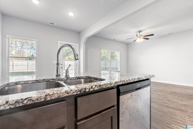 kitchen featuring light stone countertops, stainless steel dishwasher, ceiling fan, sink, and hardwood / wood-style floors