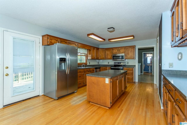 kitchen with a healthy amount of sunlight, a center island, light wood-type flooring, and appliances with stainless steel finishes