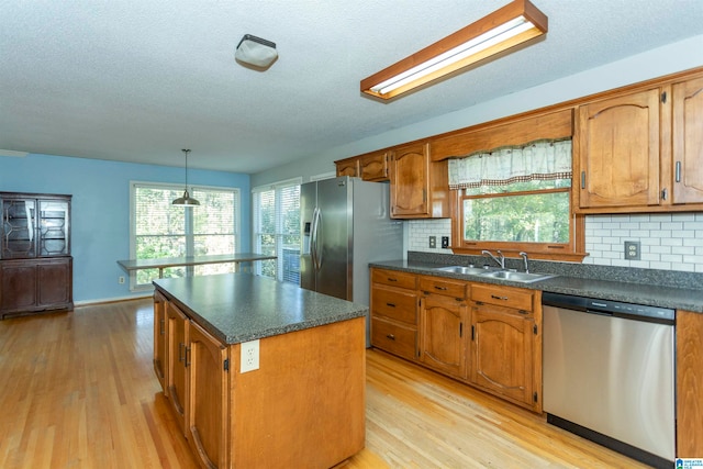 kitchen featuring appliances with stainless steel finishes, light hardwood / wood-style flooring, a kitchen island, and sink