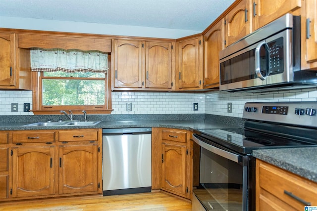 kitchen featuring stainless steel appliances, tasteful backsplash, light hardwood / wood-style floors, and sink