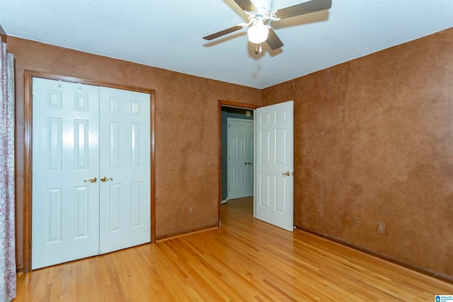 unfurnished bedroom featuring a textured ceiling, a closet, hardwood / wood-style flooring, and ceiling fan