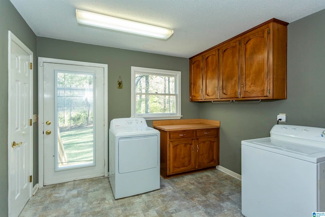 clothes washing area with cabinets, a textured ceiling, and washer and dryer