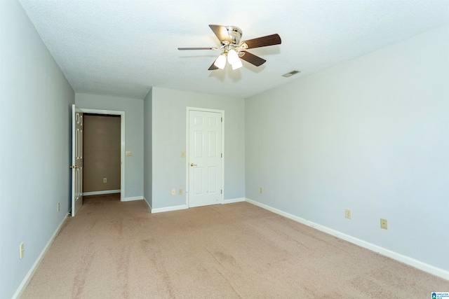 unfurnished bedroom featuring ceiling fan, light colored carpet, and a textured ceiling