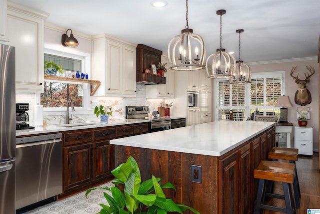 kitchen with ornamental molding, stainless steel appliances, sink, a notable chandelier, and a center island