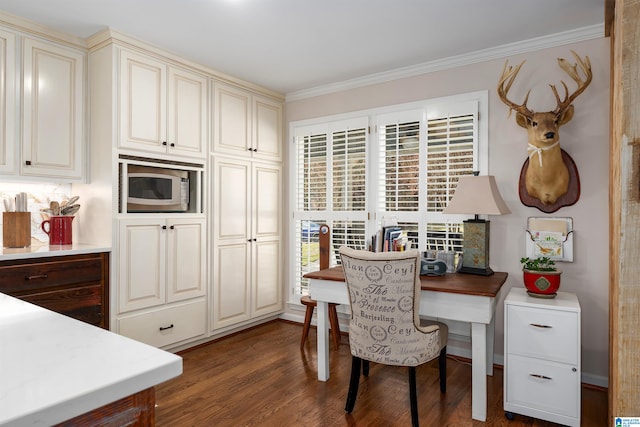 kitchen with cream cabinets, dark hardwood / wood-style flooring, stainless steel microwave, and ornamental molding