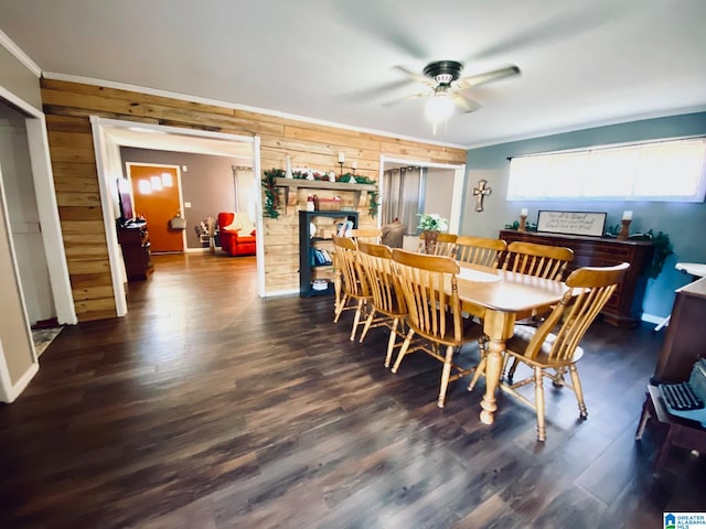 dining room with ceiling fan, wood walls, ornamental molding, and dark wood-type flooring