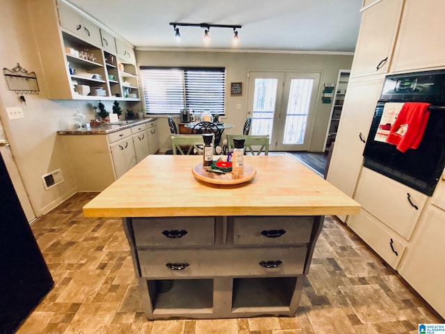 kitchen with oven, a kitchen island, ornamental molding, and light hardwood / wood-style floors