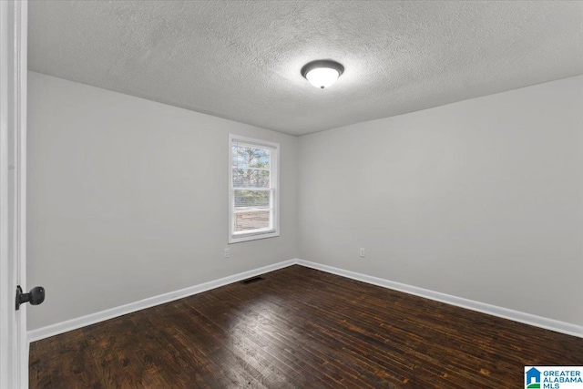 spare room with dark hardwood / wood-style flooring and a textured ceiling