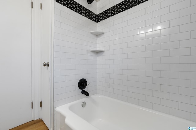 bathroom featuring wood-type flooring and tiled shower / bath