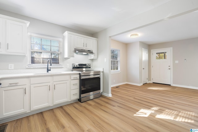 kitchen with white cabinets, stainless steel electric range, sink, and a wealth of natural light