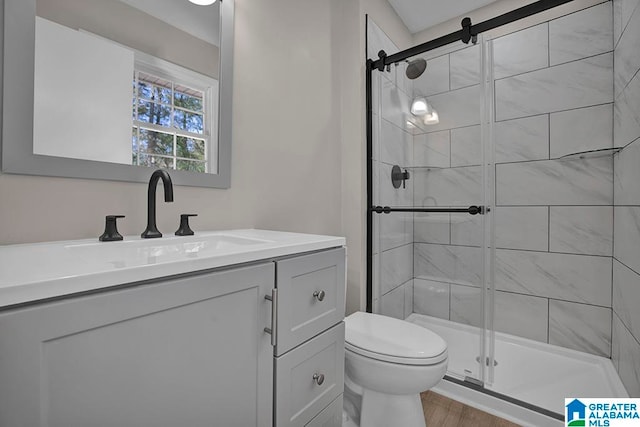 bathroom featuring vanity, hardwood / wood-style flooring, toilet, and walk in shower