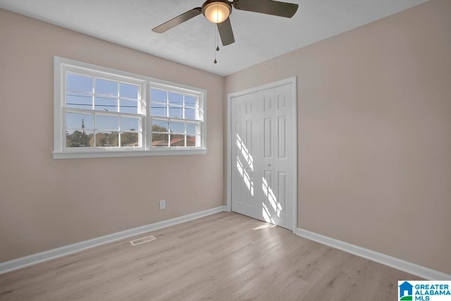 unfurnished bedroom featuring a closet, light hardwood / wood-style flooring, and ceiling fan