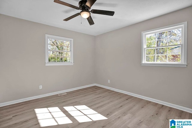 spare room featuring ceiling fan, a wealth of natural light, and light hardwood / wood-style flooring