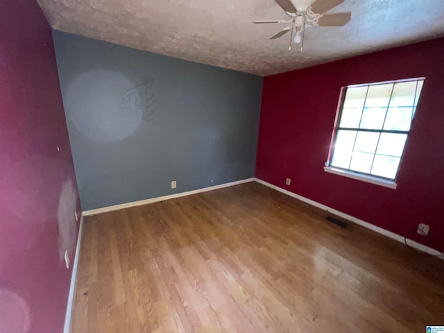 spare room with ceiling fan, wood-type flooring, and a textured ceiling