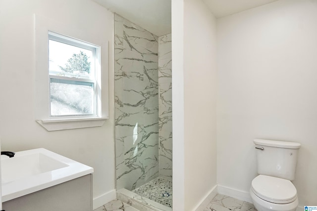 bathroom with a tile shower, vanity, and toilet