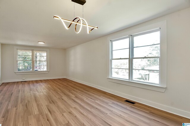 empty room featuring light hardwood / wood-style floors and a notable chandelier