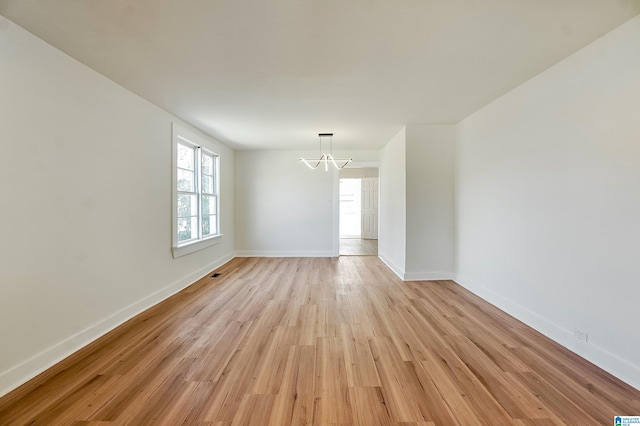 unfurnished room with a chandelier and light hardwood / wood-style floors