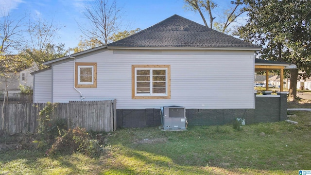 view of side of property featuring central AC unit and a lawn