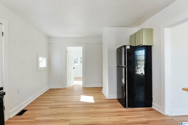 kitchen with green cabinets, black refrigerator, and light hardwood / wood-style floors