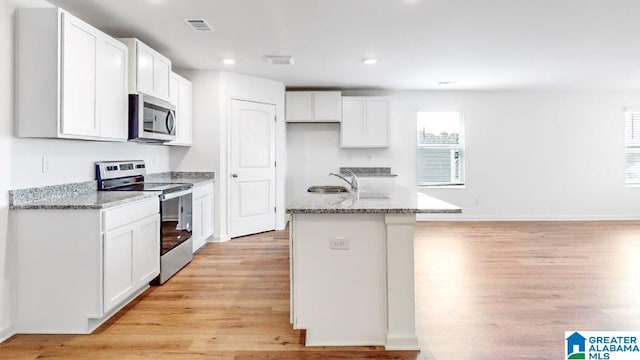 kitchen featuring light hardwood / wood-style flooring, stainless steel appliances, white cabinetry, and an island with sink