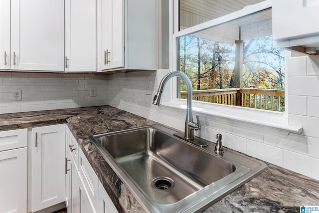 kitchen with backsplash, white cabinetry, and sink