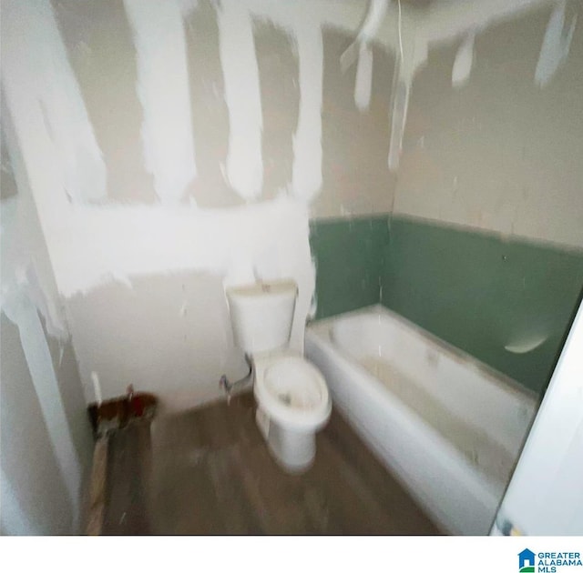 bathroom featuring hardwood / wood-style flooring, toilet, and a tub