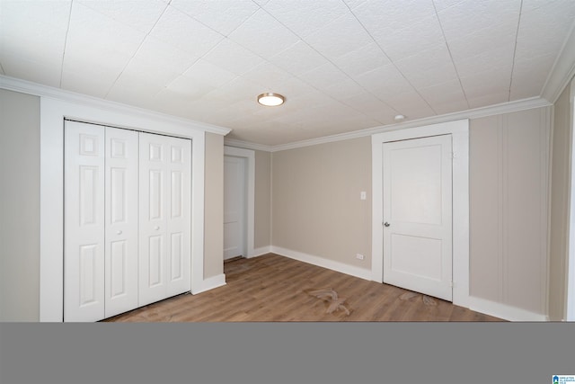 unfurnished bedroom featuring hardwood / wood-style floors, a closet, and ornamental molding