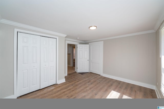 unfurnished bedroom featuring hardwood / wood-style flooring, a closet, and crown molding