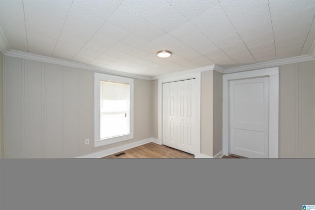 unfurnished bedroom featuring a closet, crown molding, and hardwood / wood-style floors