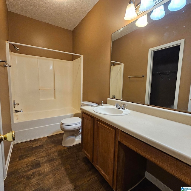 full bathroom featuring shower / bathing tub combination, vanity, hardwood / wood-style flooring, toilet, and a textured ceiling