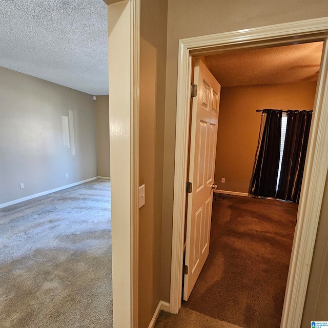 hallway featuring a textured ceiling and carpet floors