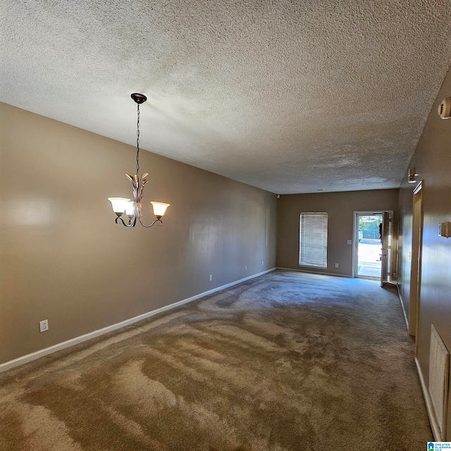 empty room featuring dark colored carpet, a textured ceiling, and a notable chandelier