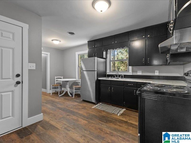 kitchen with dark wood-type flooring, sink, stainless steel refrigerator, black / electric stove, and extractor fan