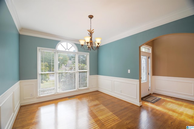 empty room featuring ornamental molding, wood-type flooring, and a notable chandelier