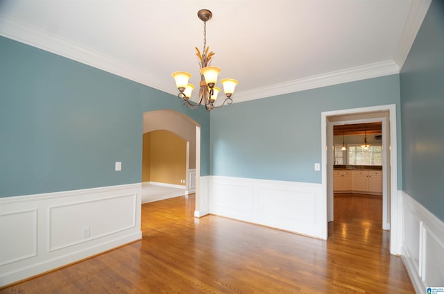 spare room with crown molding, hardwood / wood-style floors, and a notable chandelier