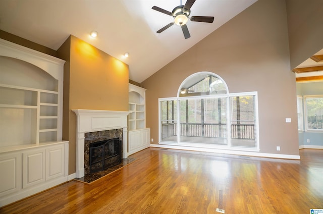 unfurnished living room featuring a high end fireplace, plenty of natural light, high vaulted ceiling, and hardwood / wood-style flooring