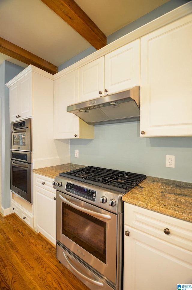 kitchen with white cabinetry, dark stone countertops, hardwood / wood-style flooring, and appliances with stainless steel finishes