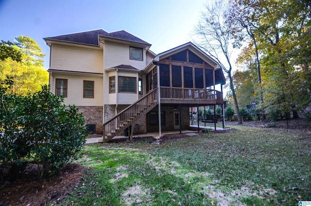 rear view of property featuring a patio, a sunroom, and a lawn