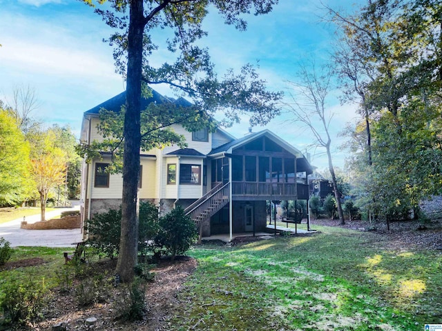 back of house with a lawn, a sunroom, and a patio