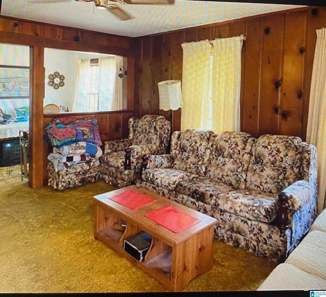 living room with ceiling fan, carpet flooring, and wood walls