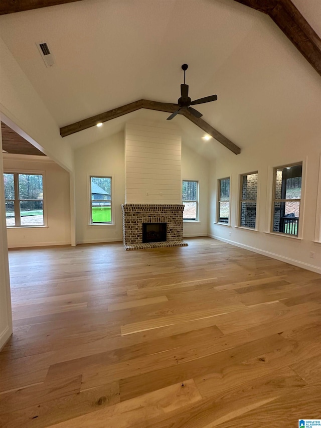 unfurnished living room with plenty of natural light, beam ceiling, and light wood-type flooring