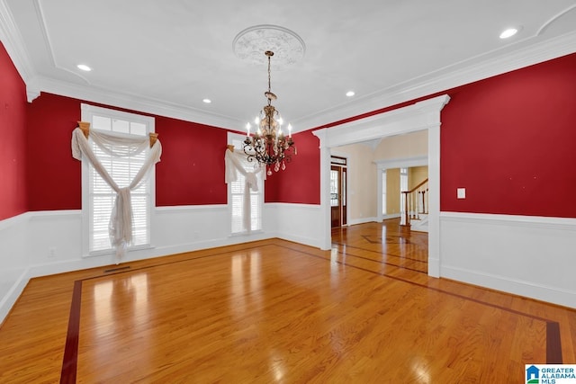 unfurnished dining area with crown molding, a chandelier, and hardwood / wood-style flooring