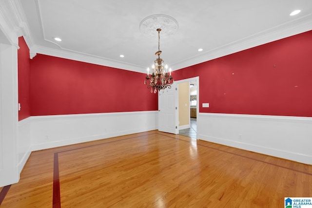 unfurnished room featuring wood-type flooring, crown molding, and a chandelier