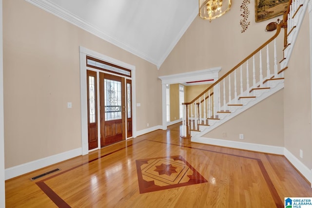 foyer featuring crown molding, hardwood / wood-style floors, high vaulted ceiling, and an inviting chandelier